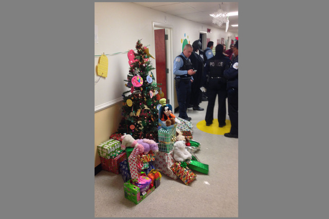<p>Police gather in the hall of a DCFS facility on Christmas morning&nbsp; to surprise the 4- and 7-year-old survivors of a deadly Englewood fire. Donated gifts for the boys are piled near a Christmas tree.</p>
