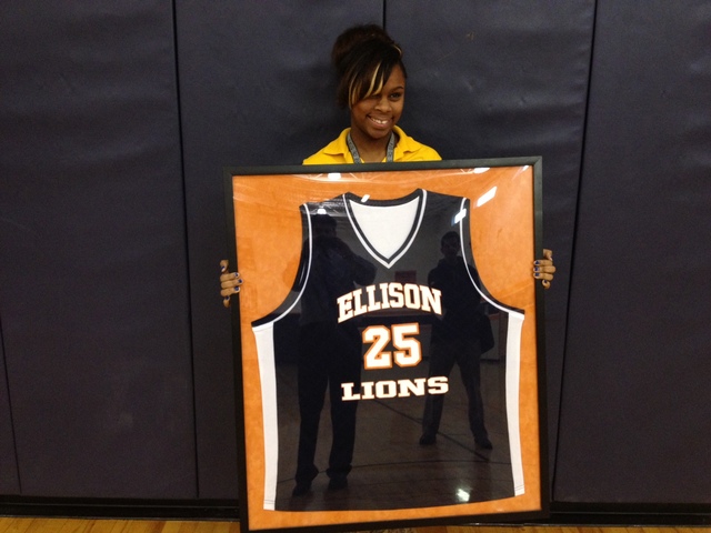 <p>CICS-Ellison senior guard Ariel Green holds the game-worn jersey of her brother, Estavion Green, who was fatally shot in 2011. Estavion's jersey hangs in the Ellison gym.</p>
