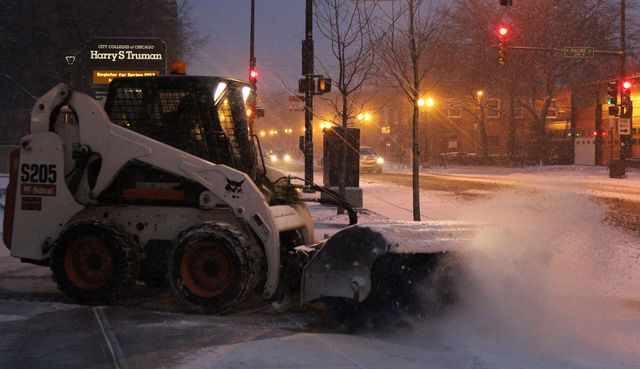 <p>A Bobcat blows away Friday morning's snow on West Wilson Avenue in Uptown.</p>
