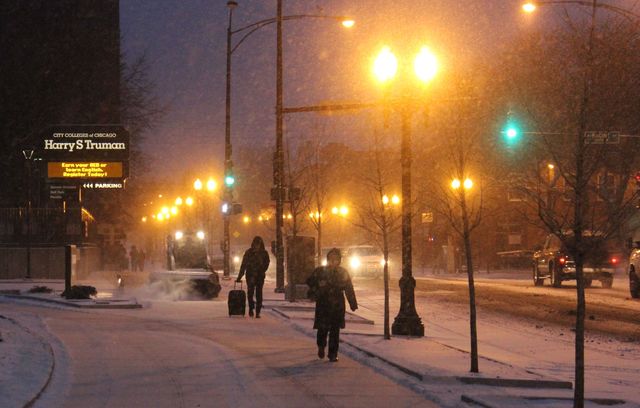 <p>Commuters make their way through Friday morning's snow near the Wilson Red Line stop in Uptown.</p>
