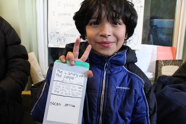 <p>Joaquin, nine, holds up an example library card for The People&rsquo;s Library, a &ldquo;micro-library&rdquo; started by Rachel Perveiler on her back porch.</p>
