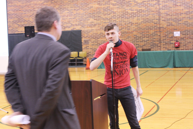 <p>Ryan Polker grabs the microphone during a public meeting about school closures. CPS officials had difficulty getting through their prepared presentation because of outbursts from the crowd.</p>
