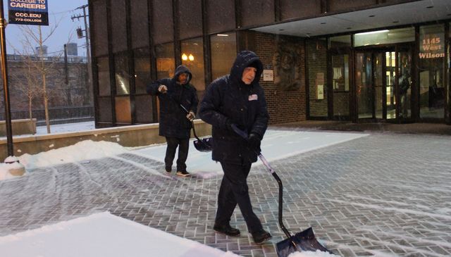 <p>Johnnie Holly (l.) and Arkady Tsilker shovel snow outside Truman College on West Wilson Avenue early Friday morning.</p>
