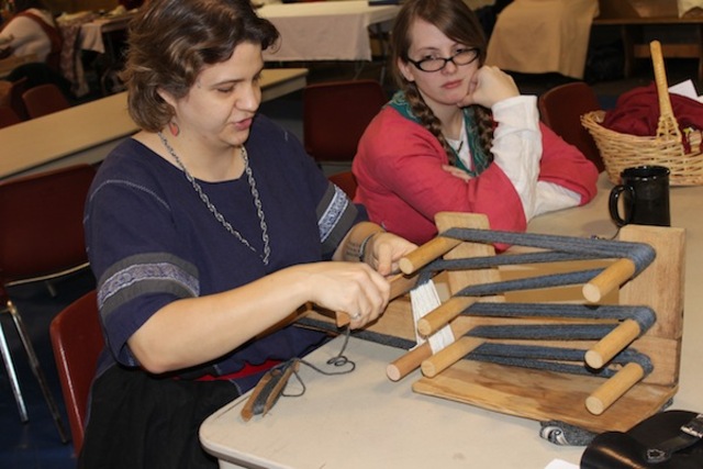<p>Jeanie Davan, of Madison, Wisc., weaves wool on an inkle loom while chatting with Marti Fuerst, of Aurora.&nbsp;</p>
