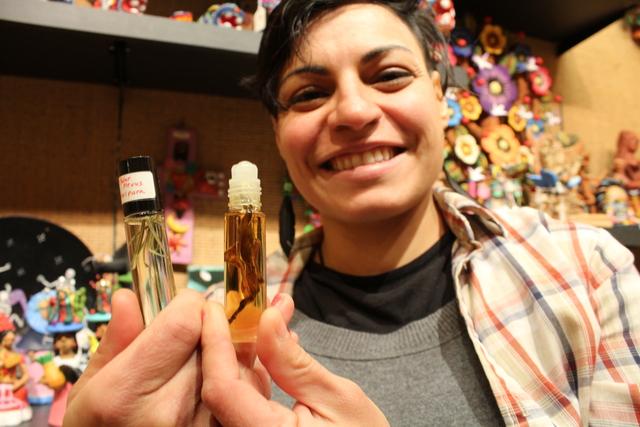 <p>Zorayda Ortiz holds up two oils from her chakra oils collection. She is about to debut a line of oils that pay homage to the Pilsen neighborhood.</p>
