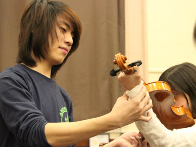 <p>Amundsen orchestra members help students at McPherson Elementary learn the basics of playing the violin.</p>
