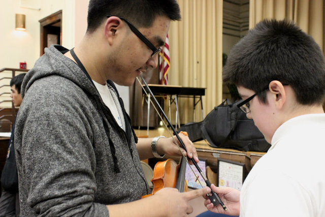 <p>Amundsen orchestra members teach students at McPherson Elementary the basics of the violin, like how to hold the bow.</p>
