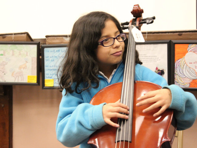 <p>A student at McPherson Elementary practices her upright bass moves during a music lesson with orchestra members from Amundsen High School.</p>
