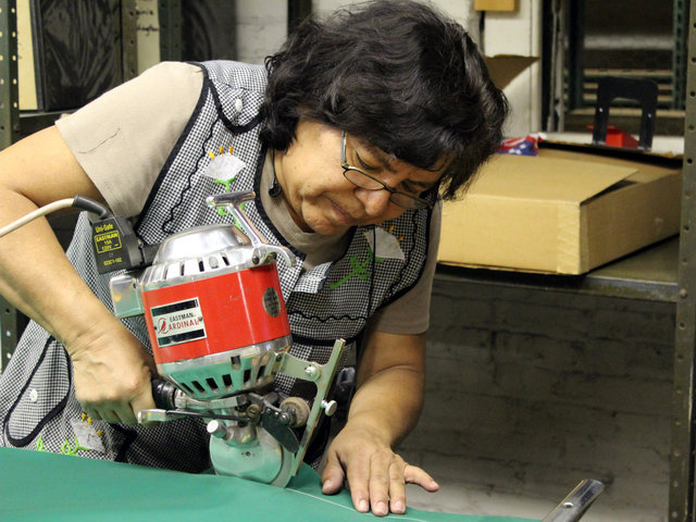 <p>Lidia Calderon, a 22-year employee of Advertising Flag Co., cuts fabric using a circular knife.</p>

