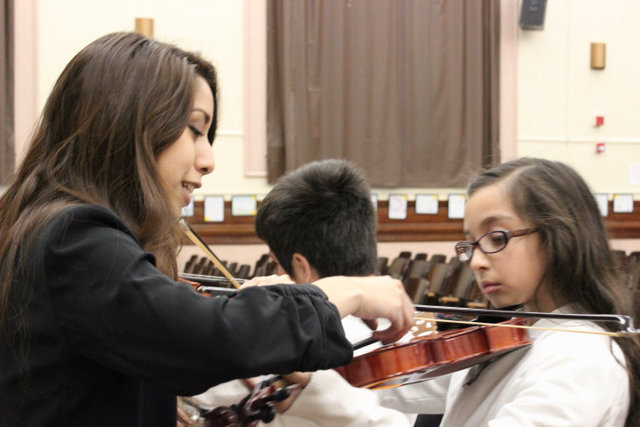 <p>Two years ago, Melisa Flores (l), a member of Amundsen High School's orchestra, had never held a violin &mdash; now she's teaching others how to play.</p>
