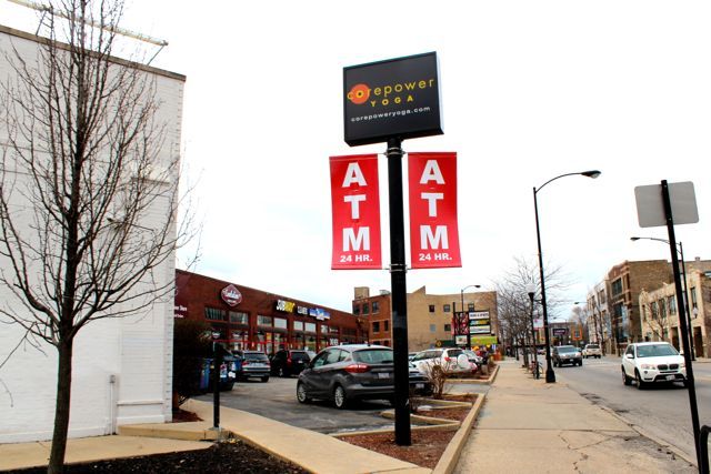 <p>A 24-Hour ATM was installed at 1704 N. Milwaukee Ave. on the southern end of a strip mall, in front of a handicap parking space, obscured by a garbage bin and next to a wall and bush. A security camera is positioned above the machine along with bright lights.</p>
