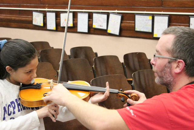<p>Sean Reidy, orchestra director at Amundsen High School, provides violin instruction to a student at McPherson Elementary.</p>
