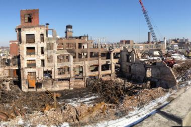Demolition and cleanup work continue at the site of a former warehouse that caught fire in January.