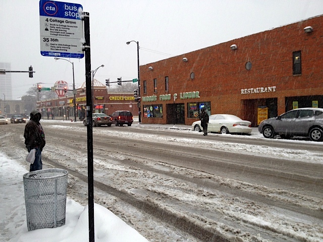 <p>A man waits for a bus at 35th Street and Indiana Avenue during a snow storm Tuesday.</p>
