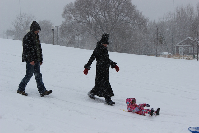 <p>A married couple take their two-year-old daughter sledding for the first time Tuesday.</p>
