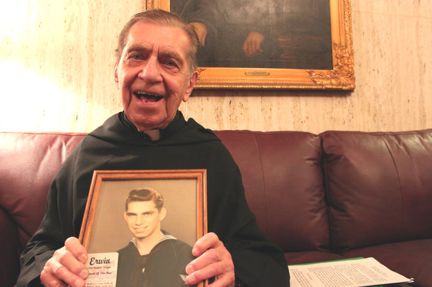 The Rev. Erwin Dodge displays a picture of himself from 1943. Dodge lives in the monastery at St. Rita High School in Ashburn. Dodge served in the Navy and was instrumental in having the memorial installed outside of the chapel at the all-boys Catholic high school.