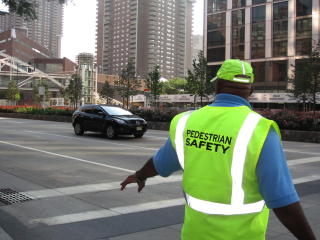Pedestrian managers help people cross West Street in Lower Manhattan. 
