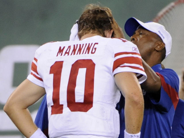 A trainer helps New York Giants quarterback Eli Manning during the second quarter of a preseason NFL football game against the New York Jets at New Meadowlands Stadium in East Rutherford, N.J., Monday, Aug. 16, 2010. Manning suffered a big gash to the left side of his temple and was forced to leave the game. (AP Photo/Bill Kostroun)