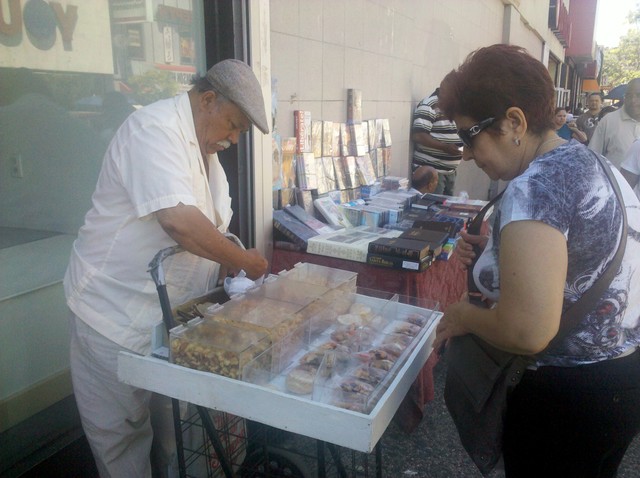 A man sells nuts and dried fruit from a cart on 181st Street.