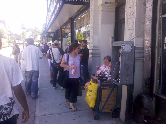 A woman sells items from a cart on 181st Street.
