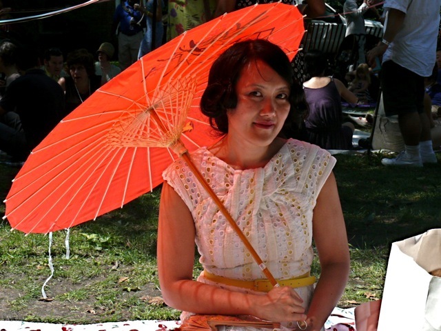 A persimmon parasol paired with a vintage eyelet yellow and white dress.