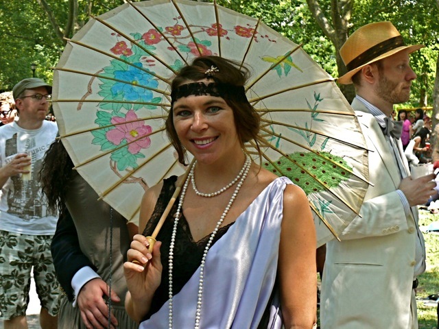  A black and white flapper-inspired ensemble accessorized with a lace headband, ropes of pearls and brightly colored floral parasol 
