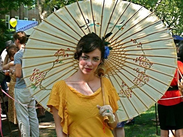  A bias cut 30s high-waist dress accessorized with a blue floral and ostrich feather fascinator, printed parasol and crocheted gloves.
