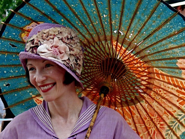 Heidi Rosenau, an avid vintage collector and historian is wearing a lavender nautical ensemble with a matching cloche hat asymmetrically decorated with silk flowers. Her parasol is an antique from the jazz era.