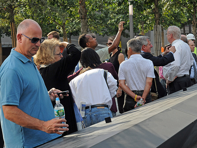 A man reads the names of 9/11 victims that are written in bronze surrounding the pools. 