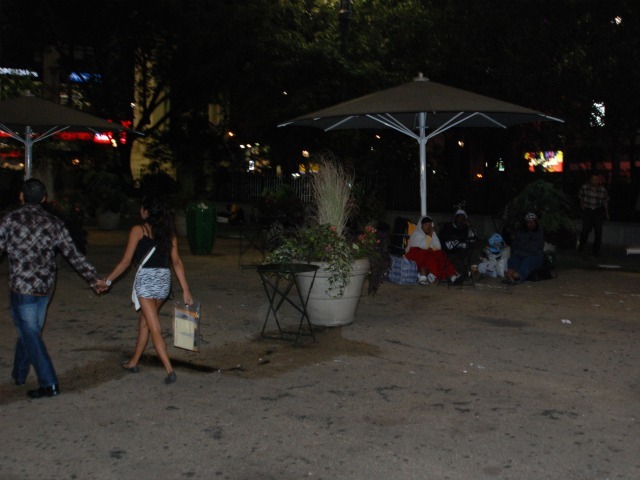 A couple strolls past a group of people camped in the plaza in front of Macy's Herald Square.