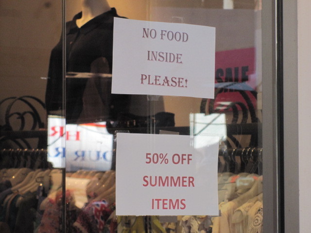 A sign in he window of a Mulberry Street clothing store warns against bringing food inside.
