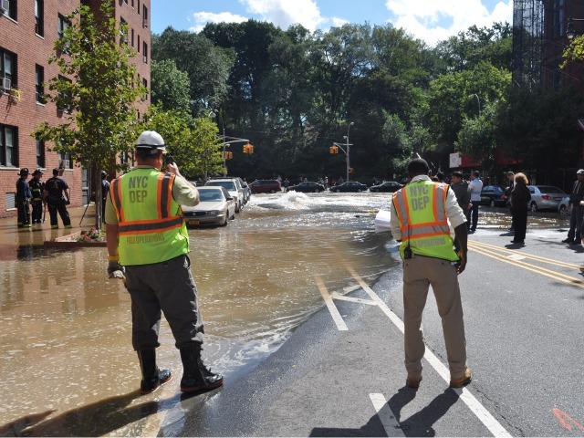 Workers watch as water is pumped onto the street.