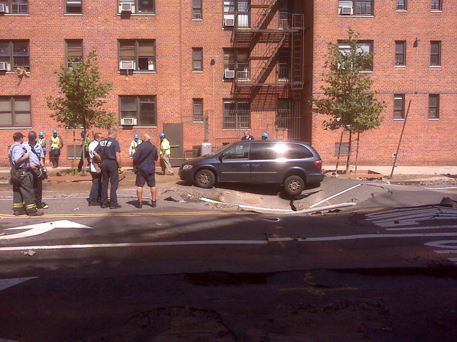 A minivan perches precariously on 106th st near Central Park West, as emergency personnel attempt to remove it to excavate the broken water main beneath, Sept. 19, 2011. 