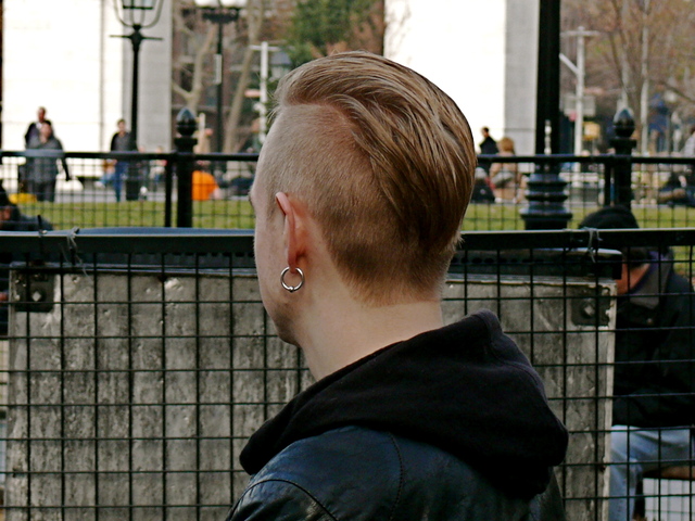 Detail of Trond B.'s asymmetric shaved curtain hairstyle, with a black cotton hoodie and biker.