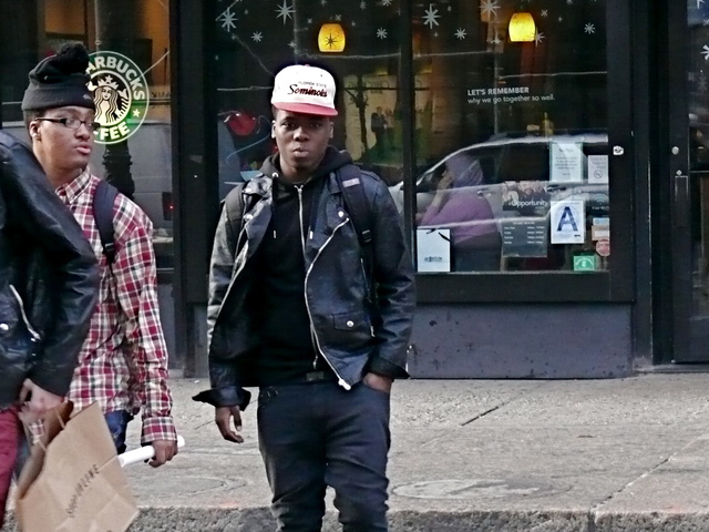 A biker jacket styled with an urban edge with drop-crotch jeans and a hip hop style baseball cap on Broadway.