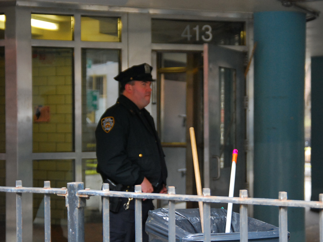 An officer stands outside of the entrance to the crime scene at the Fulton Houses on Dec. 12, 2011.