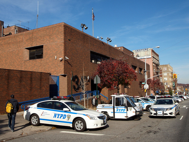 A police car double parks outside the 34th Precinct.