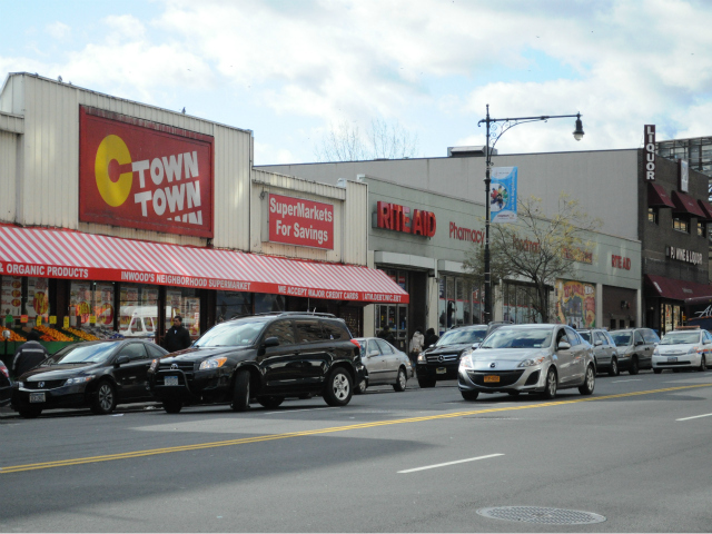 A black SUV double parked outside C-Town in Inwood as a traffic police car approaches. The driver of the car returned to the empty vehicle and moved before being towed. 