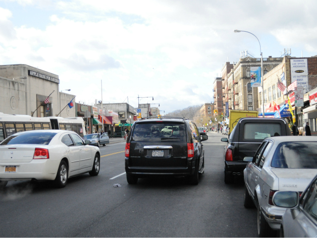 A double-parked black minivan on Broadway outside a local church.
