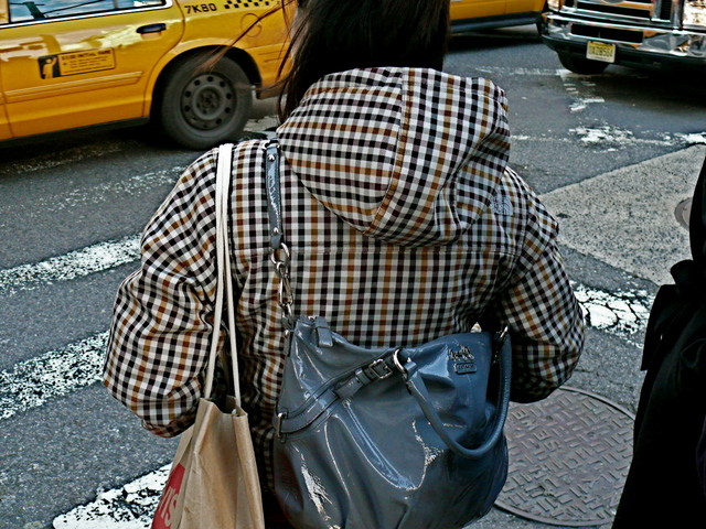 Nylon check hoodie jacket and contrasting patent leather shoulder bag on Broadway in SoHo.