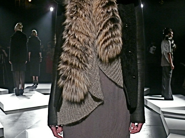 A detail of a black shearling coat with leather sleeves and a coiling cashmere sweater.