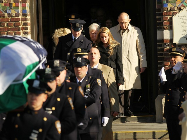 Mourners follow the flag-draped casket of NYPD officer Peter Figoski, who was killed last week while responding to a robbery, as its brought out following his funeral at St. Joseph’s Church on December 19, 2011 in Babylon, New York.