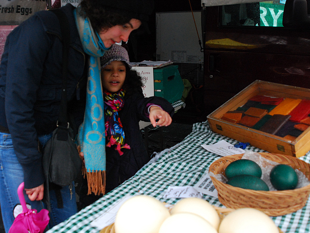Lower East Side resident Kimaya, 6, points to the basket of emu eggs. She noticed them on her walk through the farmer's market with babysitter Lauren Maettler, 24.