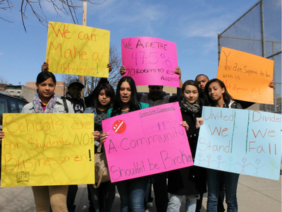 Students from Schomburg hold up signs shortly after walking out of their school to protest the DOE's co-location plan.