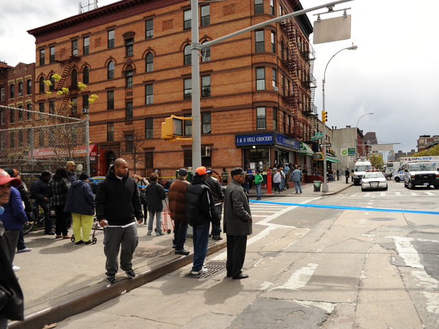 People stand on the edge of the crime scene at First Avenue and East 119th Street. 
