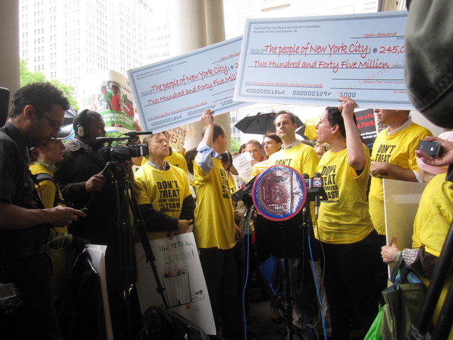 Residents for Sane Trash Solutions held up mock checks referring to what they say is the city's ever increasing costs for the East 91st Street marine transfer station. 