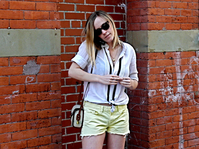 Knotted schoolgirl uniform blouse and icy lemon gamine cut-offs in Soho.