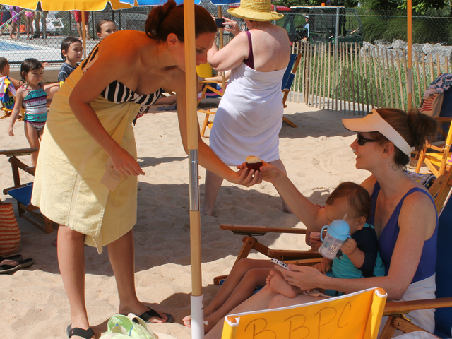 Swimmers enjoy free cupcakes under the umbrellas. 