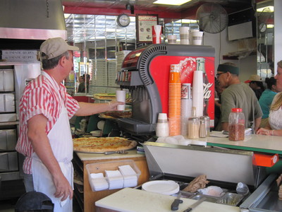 The manager of Sam's Famous Pizza fills a large cup with fountain soda for a customer.