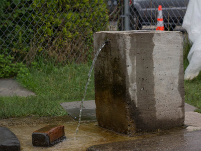<p>A spring user built a concrete structure that houses the pipe. The water flows constantly, some believing it comes from Pennsylvania before reaching the Island.</p>
